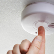 a person is pressing a button on a smoke detector