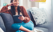 a woman is sitting on a couch with a tablet and the words upgraded comfort above her